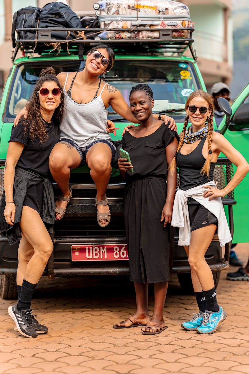 A group of diverse women posing in front of a packed adventure vehicle, symbolizing global travel and friendship.
